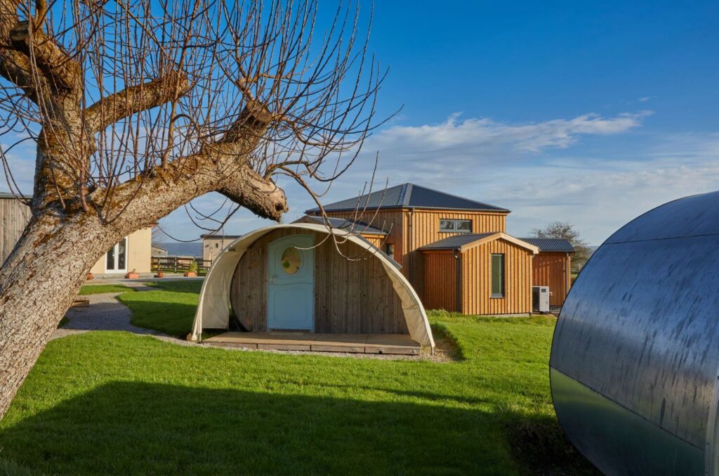 A glamping pod with our hexagonal group space in the background